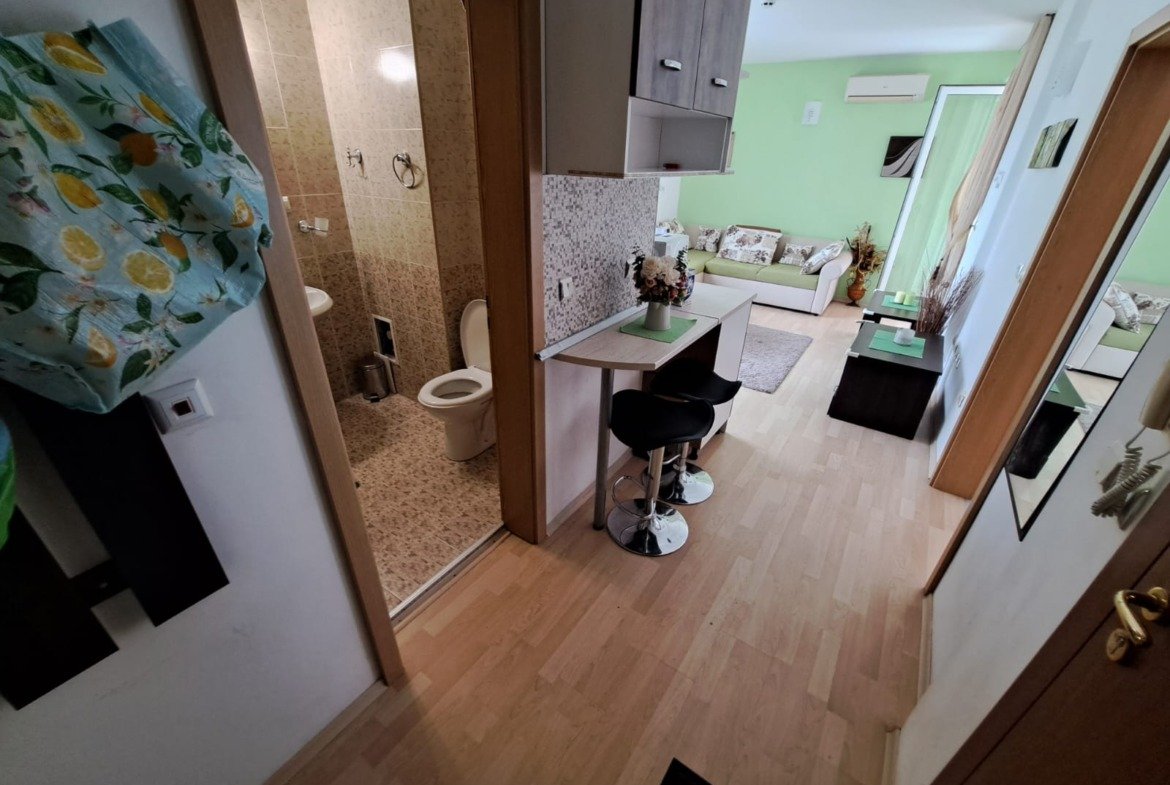 Современный интерьер двухкомнатного апартамента: кухня с барной стойкой, санузел, светлая гостиная с мягкой мебелью в зелёных тонах.