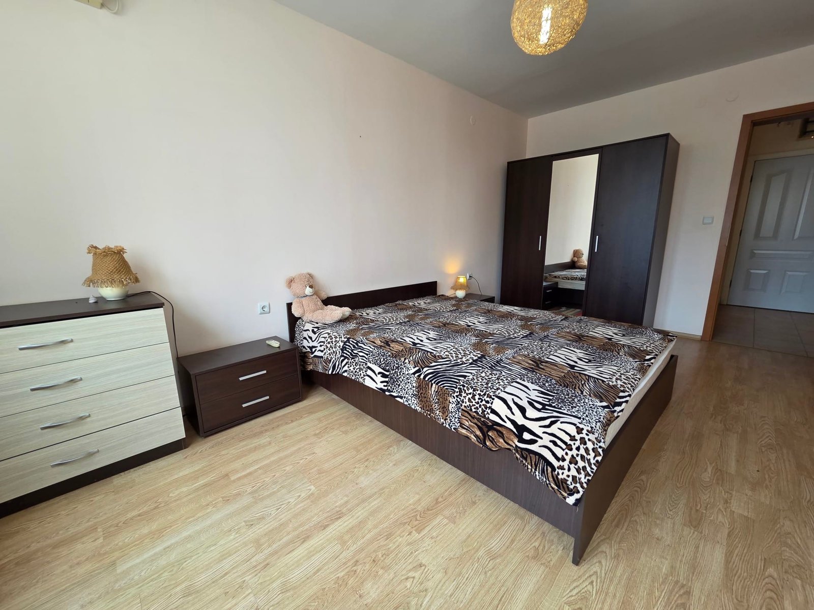 Двухкомнатный апартамент: уютная спальня с мебелью и декором Современная спальня с двуспальной кроватью, комодом и платяным шкафом, оформленная в светлых тонах и стильным текстилем.