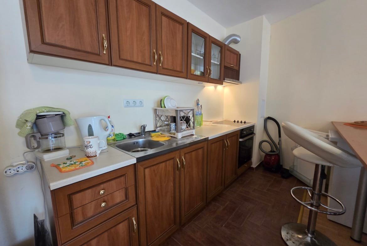 Современная кухня с деревянными шкафчиками, раковиной, плитой и барной стойкой в апартаменте Riviera Fort Beach.