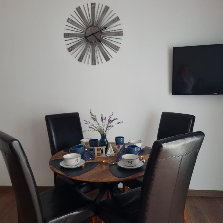 Столовая с круглым деревянным столом, черными стульями, посудой и декором из лаванды, стенами светлого тона.