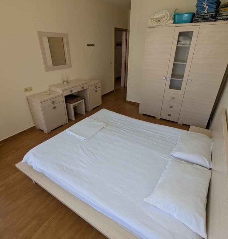 Современная спальня с односпальной кроватью, деревянной мебелью и ярким освещением, создающая уютную атмосферу.