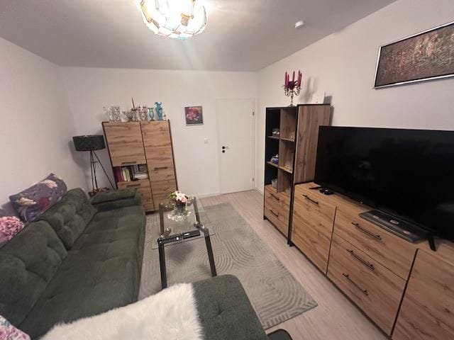 Современный интерьер трехкомнатного апартамента с уютным зеленым диваном, телевизором и деревянной мебелью.