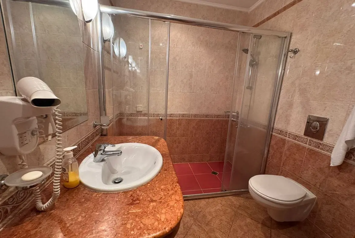 Современный санузел в трехкомнатном апартаменте Sunset Resort Современный санузел с душевой кабиной, умывальником с мраморной столешницей и сантехникой в бежевых тонах.