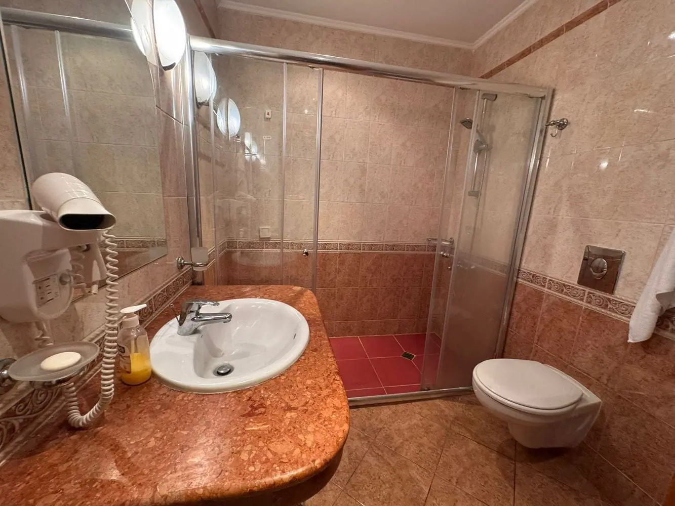 Современный санузел в трехкомнатном апартаменте Sunset Resort Современный санузел с душевой кабиной, умывальником с мраморной столешницей и сантехникой в бежевых тонах.