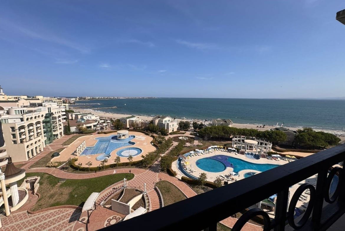 Вид на комплексы с бассейнами и пляжем у моря из трехкомнатного апартамента Sunset Resort. Ясное небо и спокойные воды.