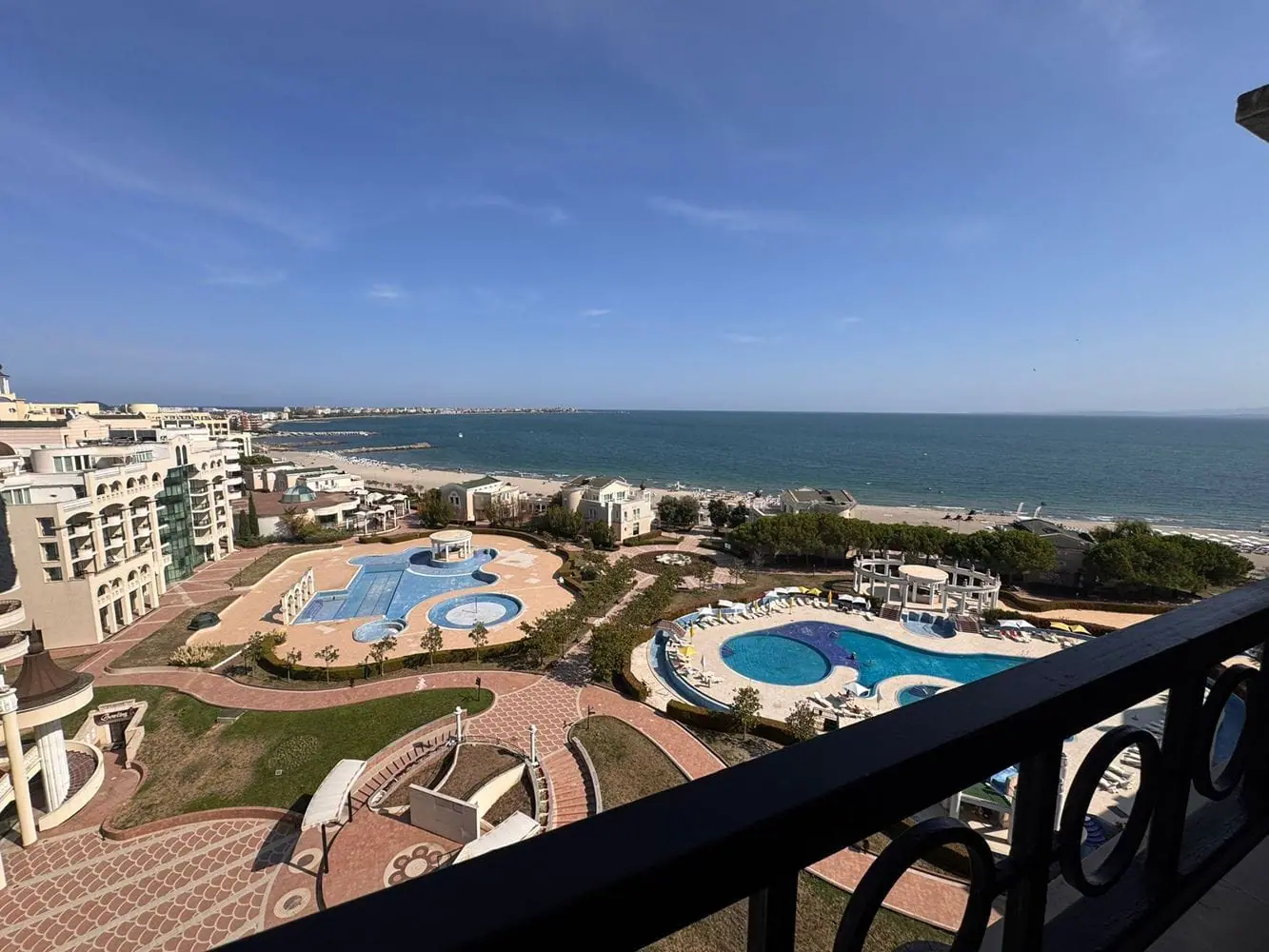 Трехкомнатный апартамент с видом на море в Sunset Resort Вид на комплексы с бассейнами и пляжем у моря из трехкомнатного апартамента Sunset Resort. Ясное небо и спокойные воды.
