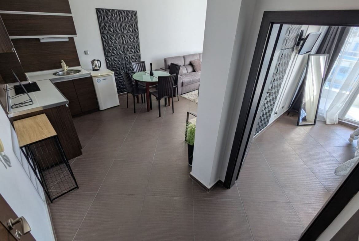 Современный двухкомнатный апартамент с кухней, обеденной зоной и светлой гостиной, большие окна с видом на улицу.