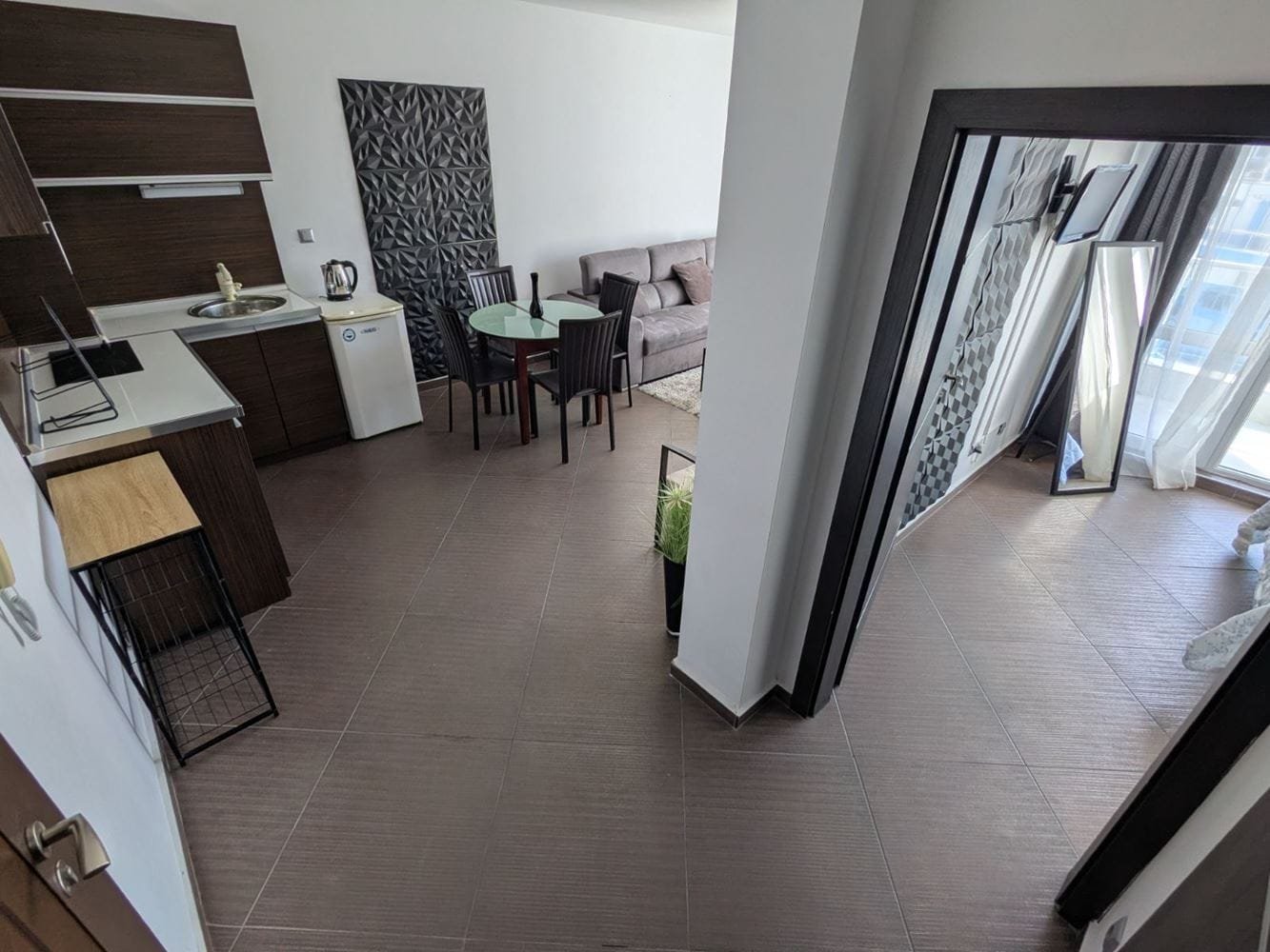 Современный двухкомнатный апартамент с кухней, обеденной зоной и светлой гостиной, большие окна с видом на улицу.