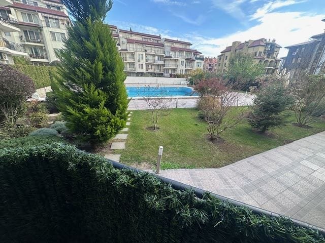 Просторный зеленый двор с бассейном, окруженный ухоженными деревьями и современными зданиями комплекса Dolphin Bay.