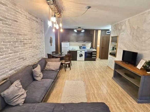 Современный двухкомнатный апартамент с белой кирпичной стеной, уютной мебелью и открытой кухней.