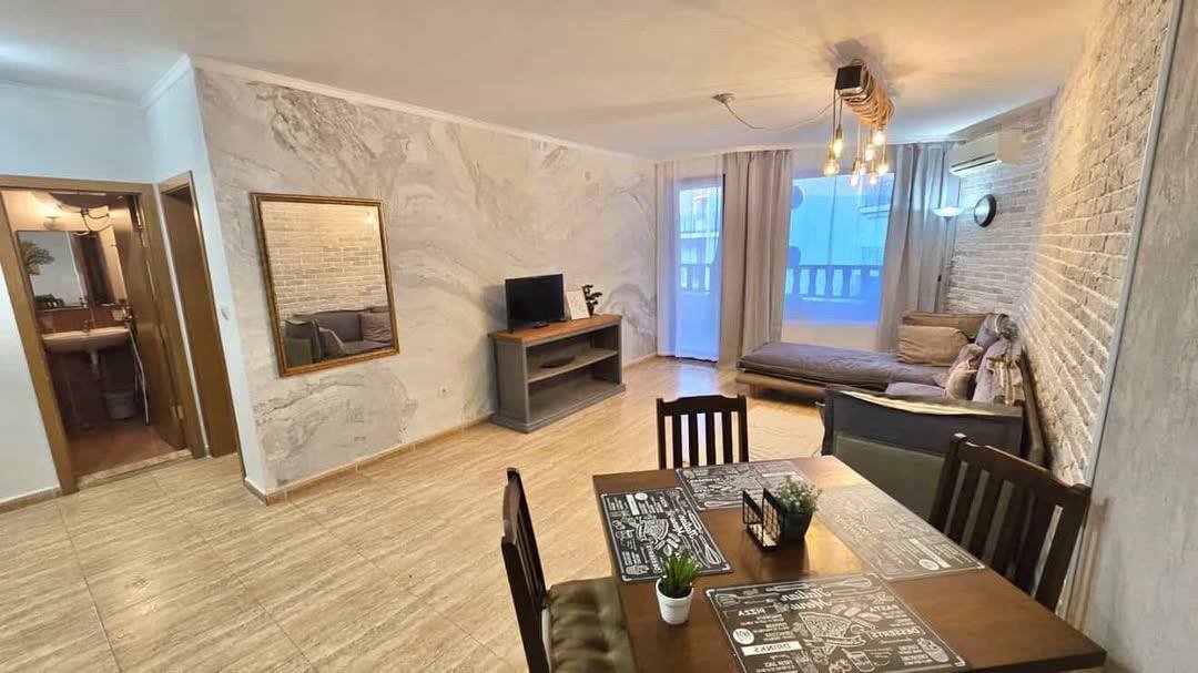 Современный интерьер двухкомнатного апартамента: уютная гостиная с диваном, телевизором, столом и мягким освещением.