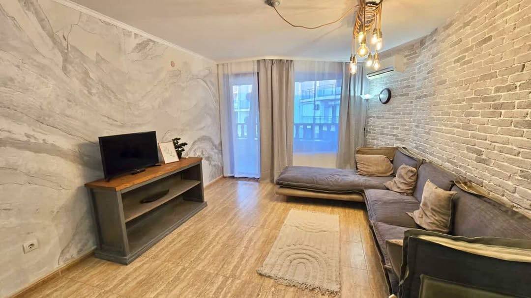 Современный двухкомнатный апартамент с уютной гостиной, телевизором, диваном и светлыми тонами стен.