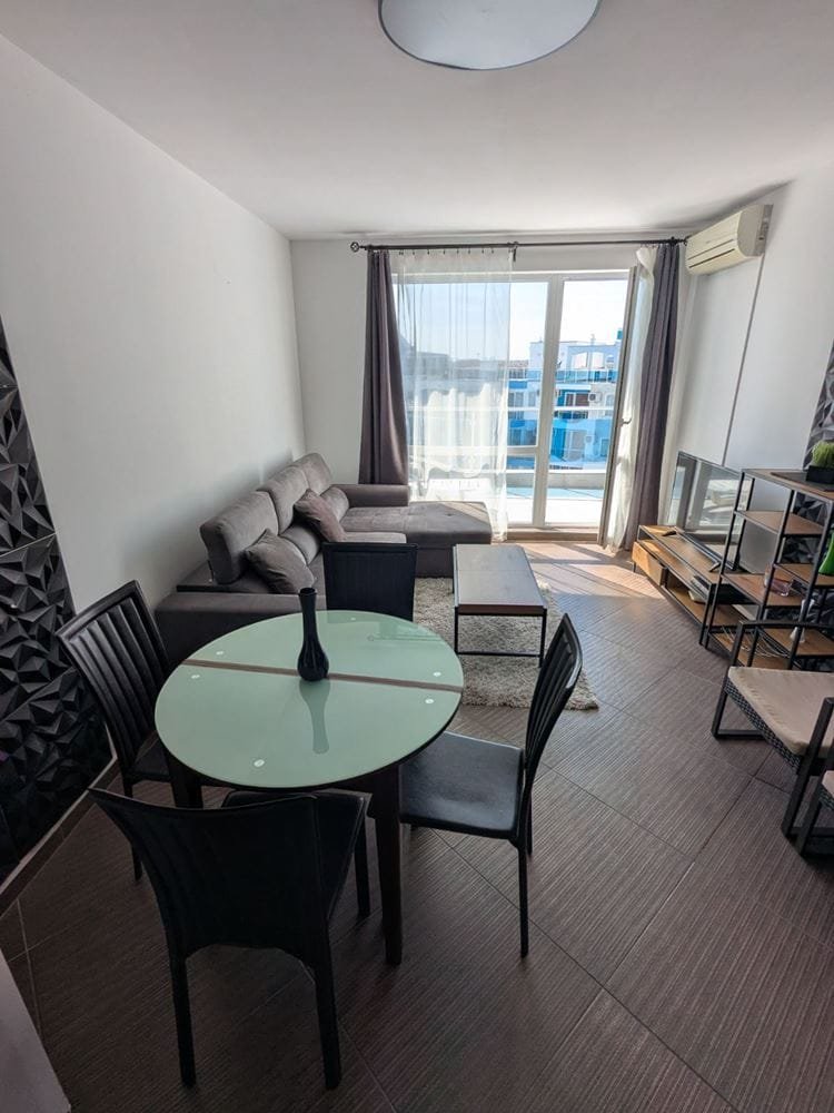 Современно оформленный интерьер двухкомнатного апартамента с обеденной зоной и видом на балкон.