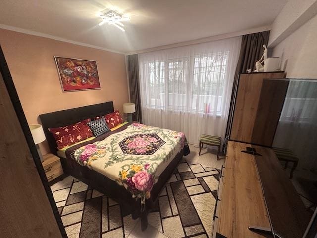 Уютная спальня с большой двуспальной кроватью, текстильными акцентами и современным телевизором, расположенная в апартаменте.