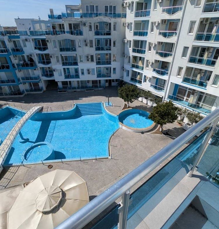 Современный двухкомнатный апартамент с видом на бассейны и двор в комплексе Odyssey, светлые тона и уютная атмосфера.