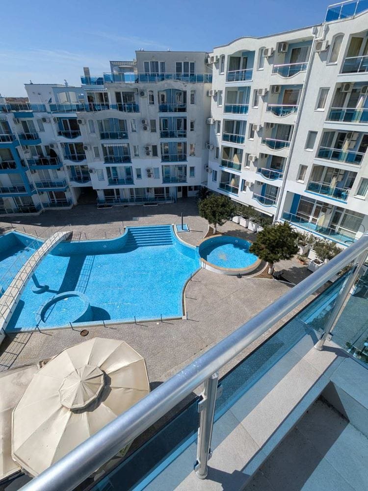 Современный двухкомнатный апартамент с видом на бассейны и двор в комплексе Odyssey, светлые тона и уютная атмосфера.