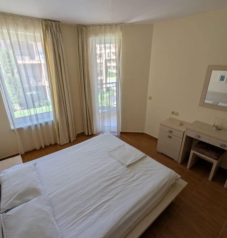 Современный спальня с большой кроватью, светлыми шторами и выходом на балкон, уютная обстановка и минималистичный дизайн.