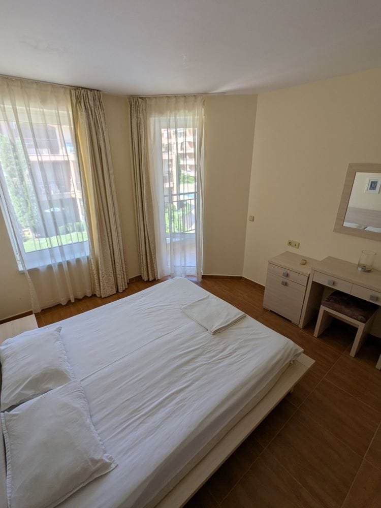 Современный спальня с большой кроватью, светлыми шторами и выходом на балкон, уютная обстановка и минималистичный дизайн.