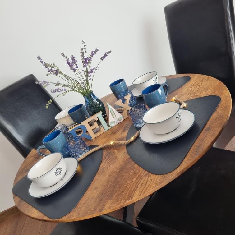Стол с чашками, вазой с лавандой и декоративной надписью "RELAX", окруженный черными стульями. Уютная атмосфера.