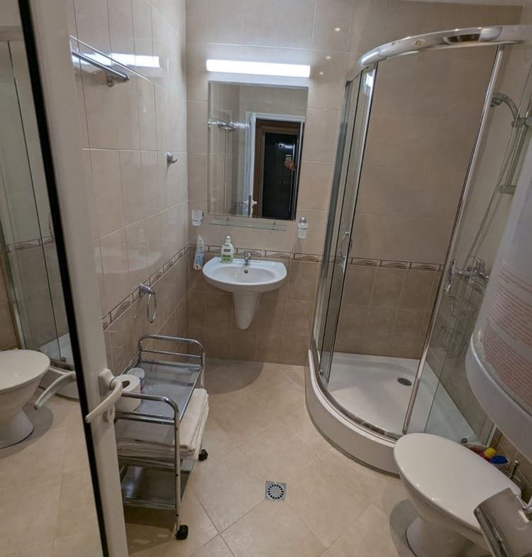 Современная ванная комната с душевой кабиной, раковиной и туалетом, выполненная в светлых тонах.