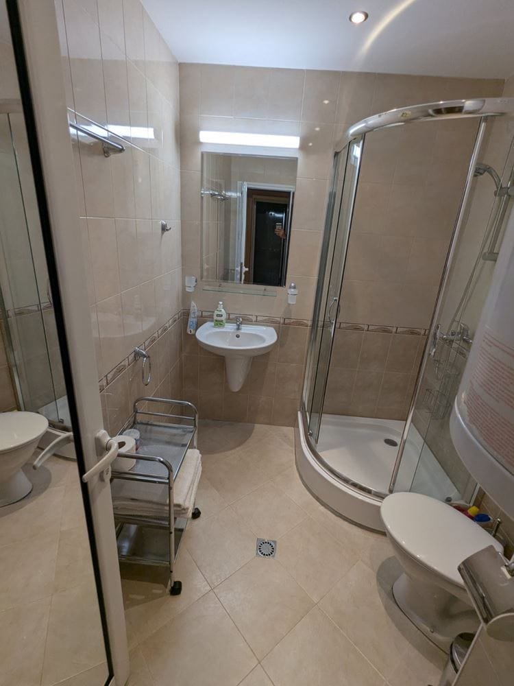 Современная ванная комната с душевой кабиной, раковиной и туалетом, выполненная в светлых тонах.