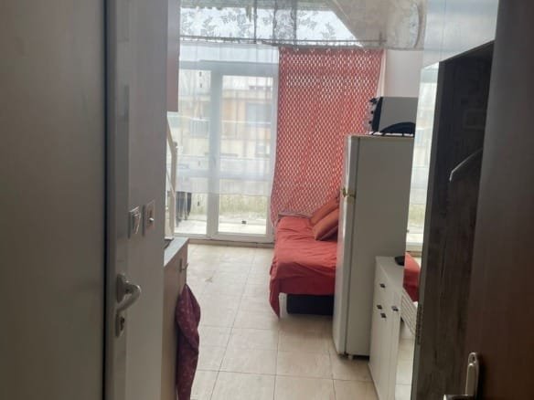 Кухонная зона и комната в студии Gerber Residence 3 с кроватью и панорамным окном. Светлые тона и уютная атмосфера.