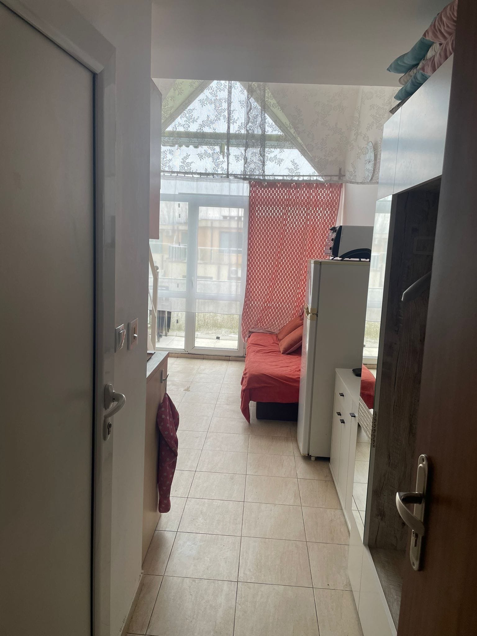 Кухонная зона и комната в студии Gerber Residence 3 с кроватью и панорамным окном. Светлые тона и уютная атмосфера.