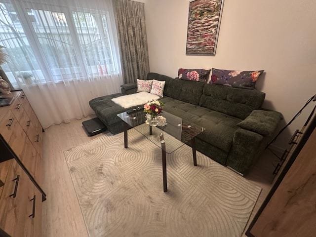 Комфортный уголок в трехкомнатном апартаменте с зеленым диваном, журнальным столиком и уютными подушками.