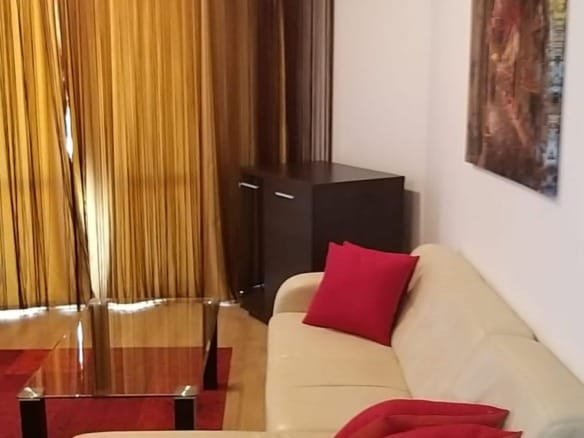 Современный двухкомнатный апартамент с уютным белым диваном, красными подушками и стильным интерьером. Большие окна с шторы.