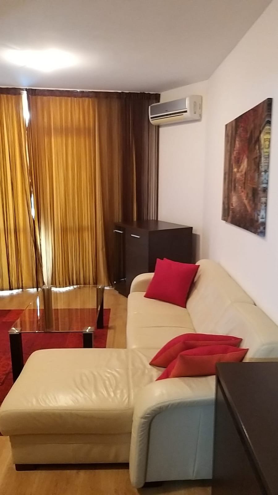 Современный двухкомнатный апартамент с уютным белым диваном, красными подушками и стильным интерьером. Большие окна с шторы.