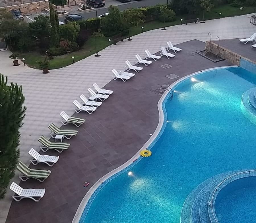 Двухкомнатный апартамент с видом на бассейн и зону отдыха, яркая вода и шезлонги для комфортного отдыха.