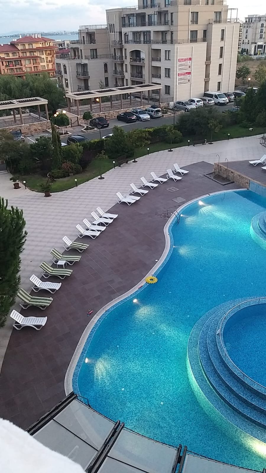 Двухкомнатный апартамент с видом на бассейн и зону отдыха, яркая вода и шезлонги для комфортного отдыха.