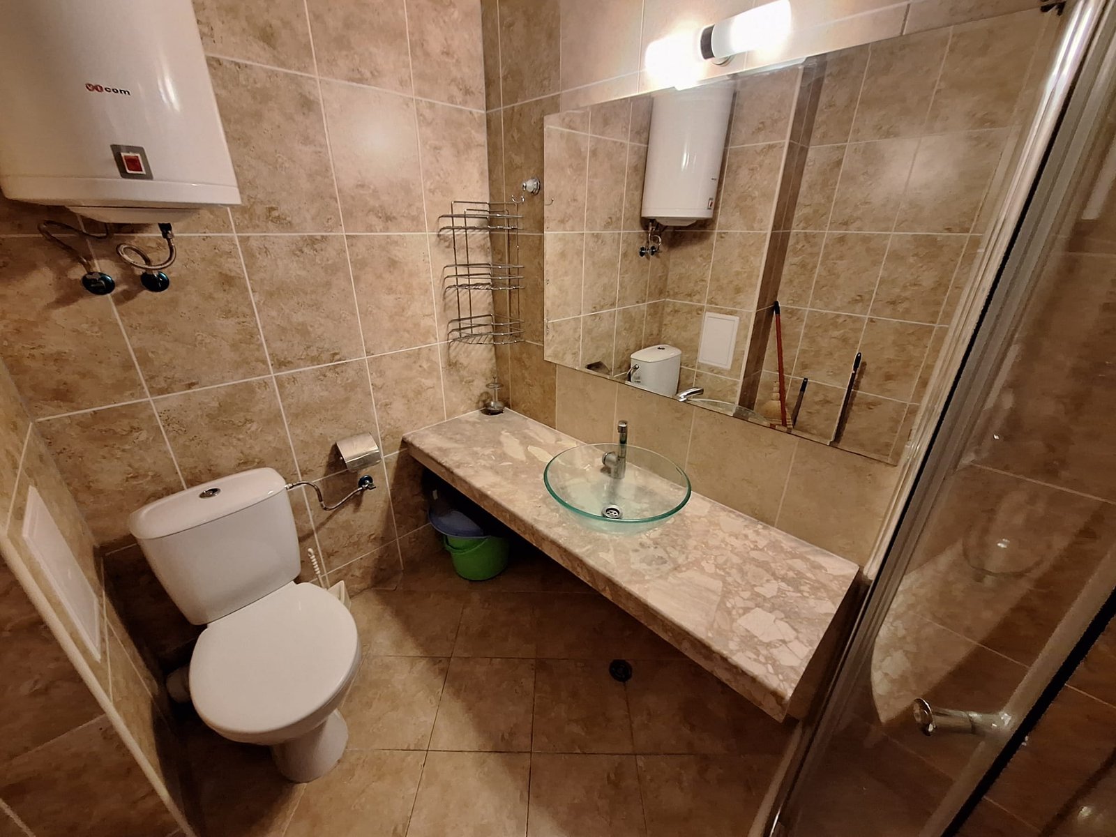 Современный санузел с плиткой в бежевых тонах, стеклянной раковиной и душевой кабинкой. Удобное оформление и чистота.