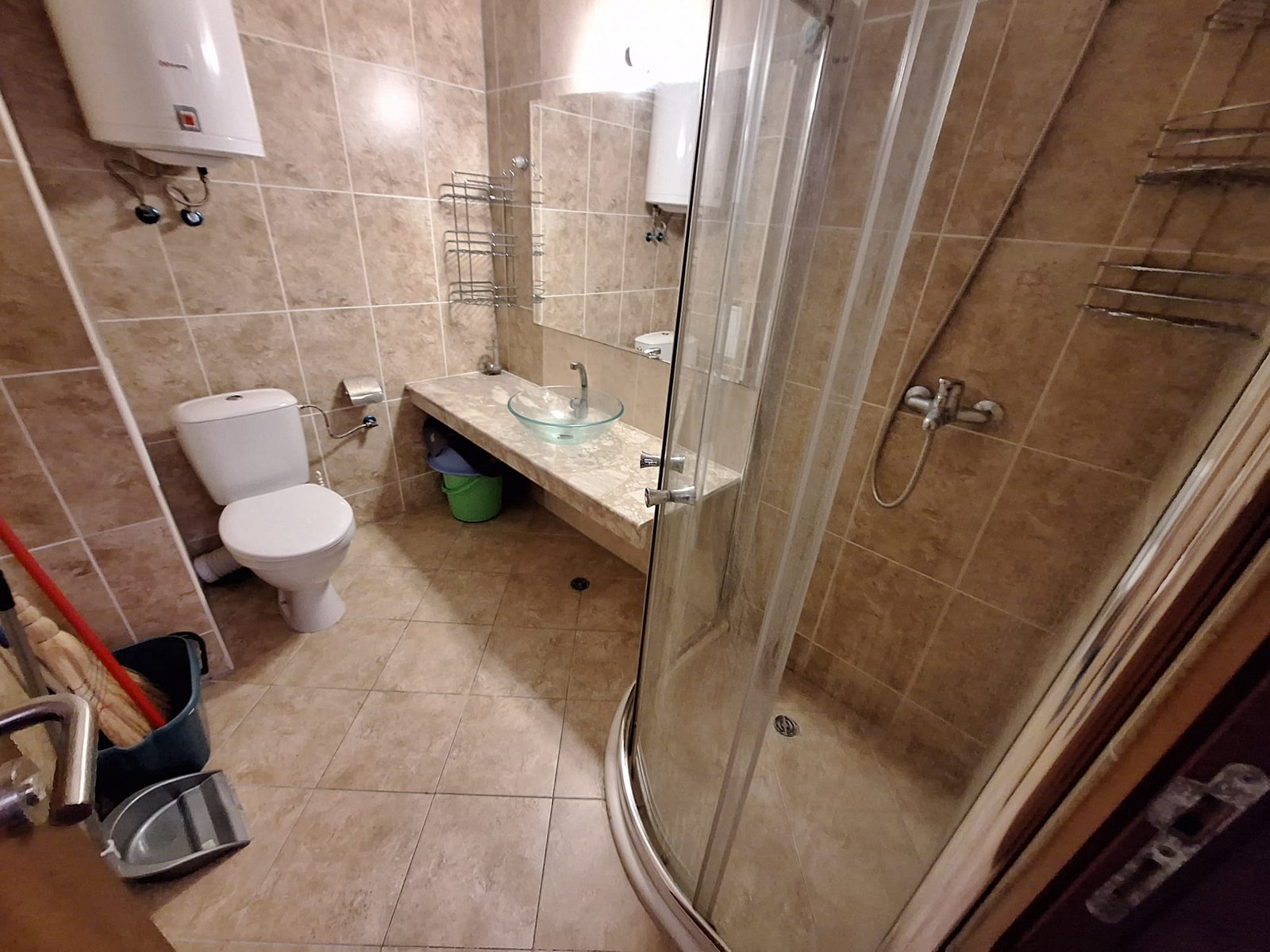 Современная ванная комната с душевой кабиной, унитазом, раковиной и плиткой бежевых тонов.