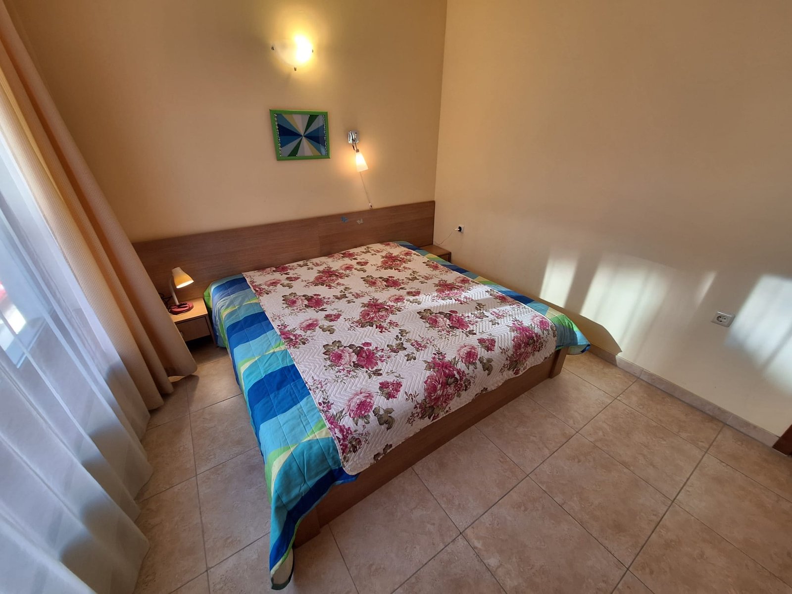 Двухкомнатный апартамент с двуспальной кроватью, ярким постельным бельем и окнами, пропускающими свет.