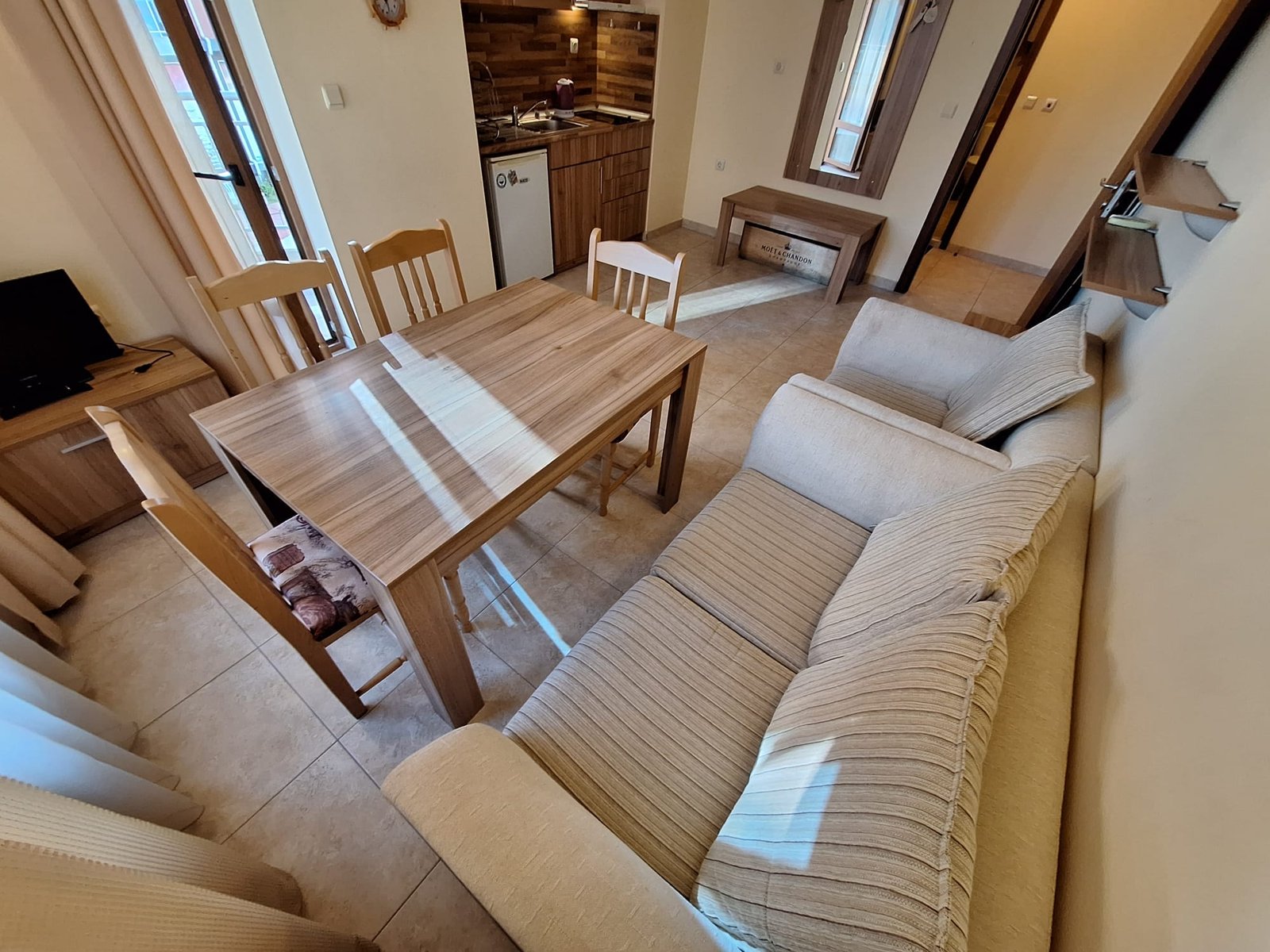 Современный интерьер двухкомнатного апартамента: уютная гостиная с диваном, обеденным столом и кухонным гарнитуром.