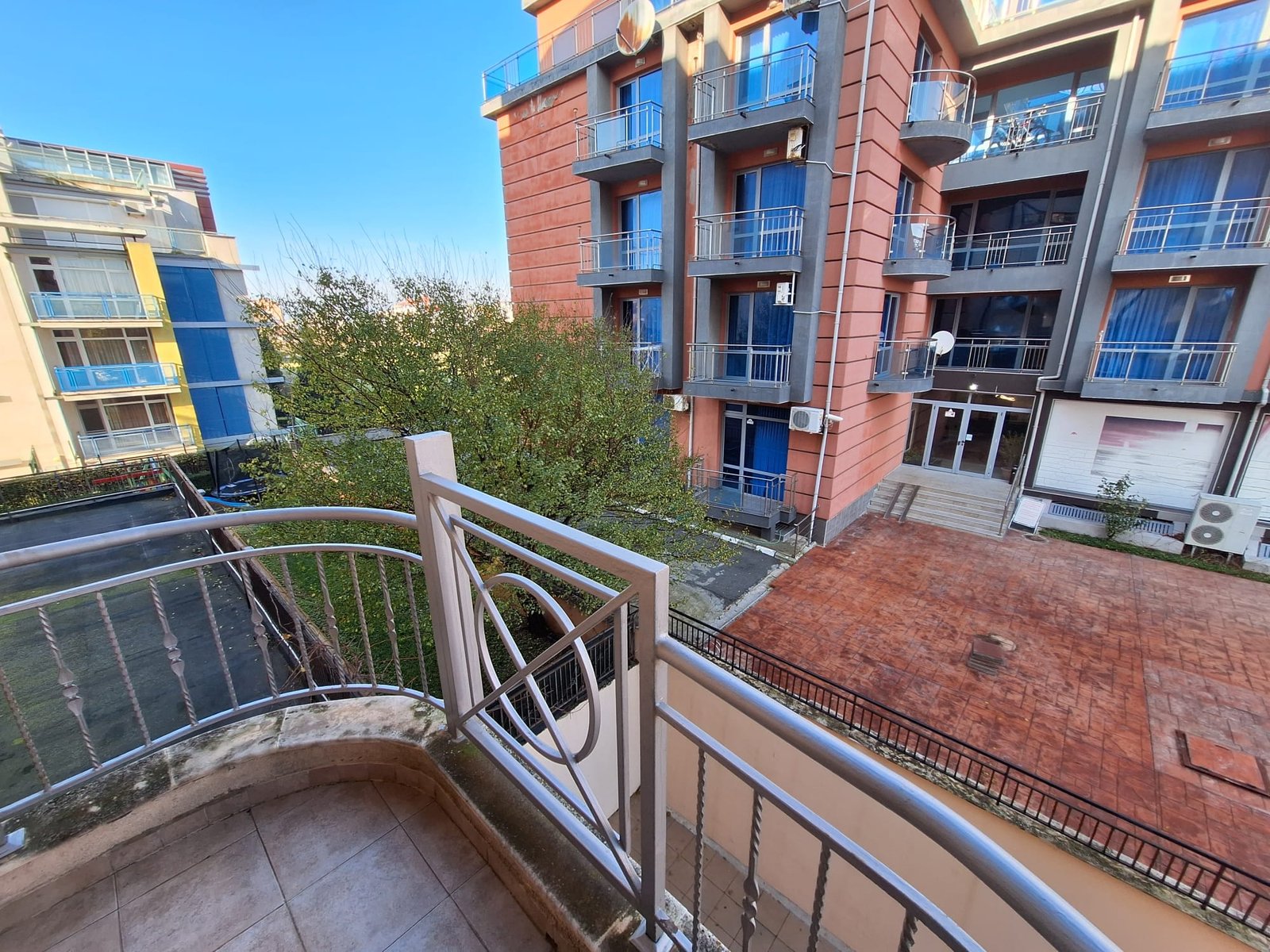 Балкон двухкомнатного апартамента с видом на зеленый двор и соседние здания в комплексе Sea Regal.