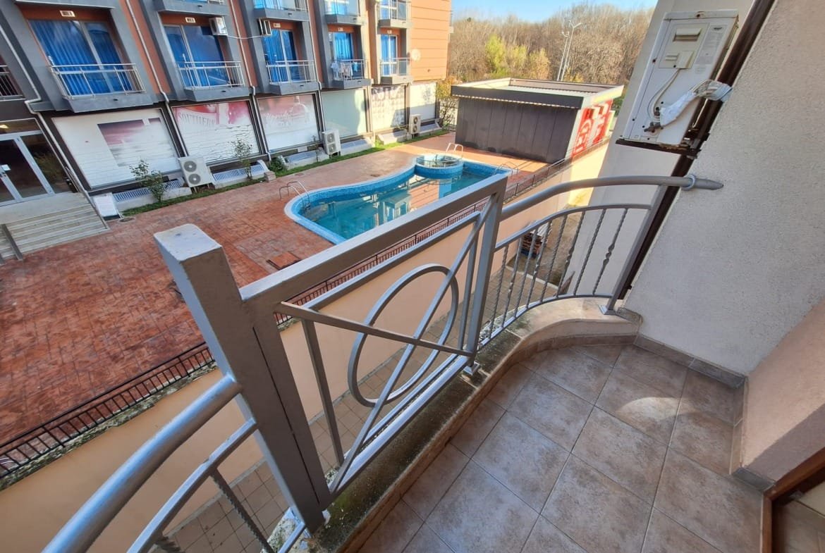 Балкон с видом на открытый бассейн и окружающую территорию комплекса Sea Regal. солнечный день, яркие цвета, современный дизайн.