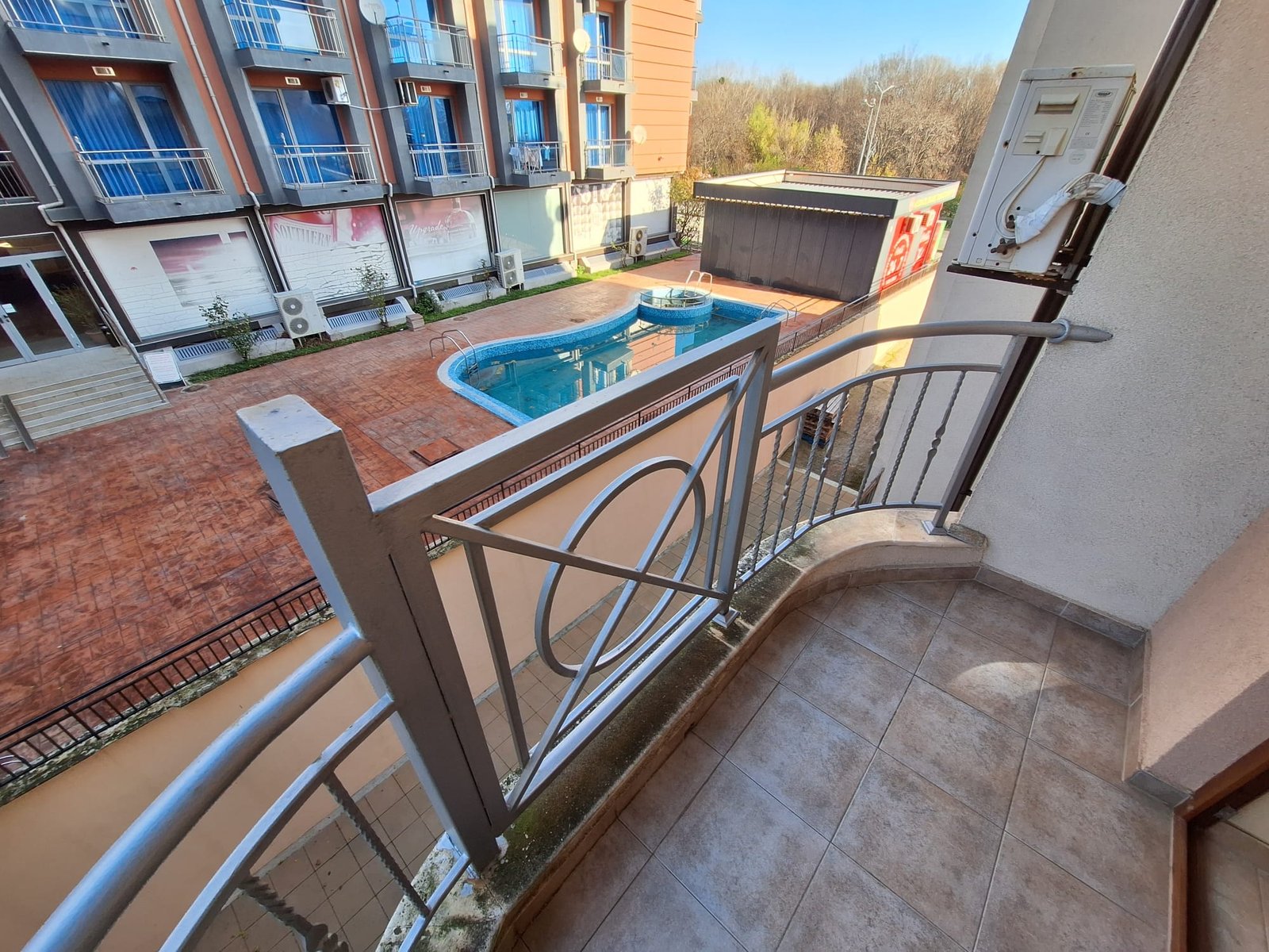 Балкон с видом на открытый бассейн и окружающую территорию комплекса Sea Regal. солнечный день, яркие цвета, современный дизайн.