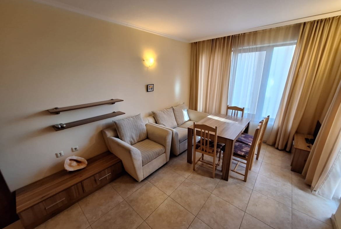 Современный интерьер двухкомнатного апартамента с мебелью, обеденной зоной и большими окнами, пропускающими естественный свет.