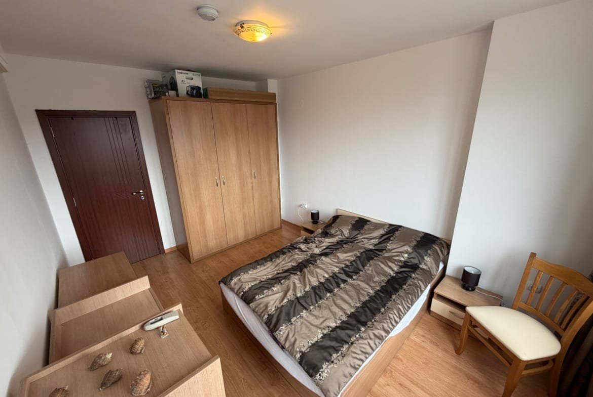 Современный интерьер трехкомнатного апартамента с деревянной мебелью, кроватью и светлыми стенами.