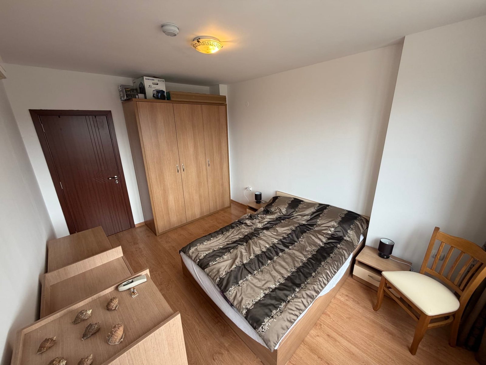 Современный интерьер трехкомнатного апартамента с деревянной мебелью, кроватью и светлыми стенами.