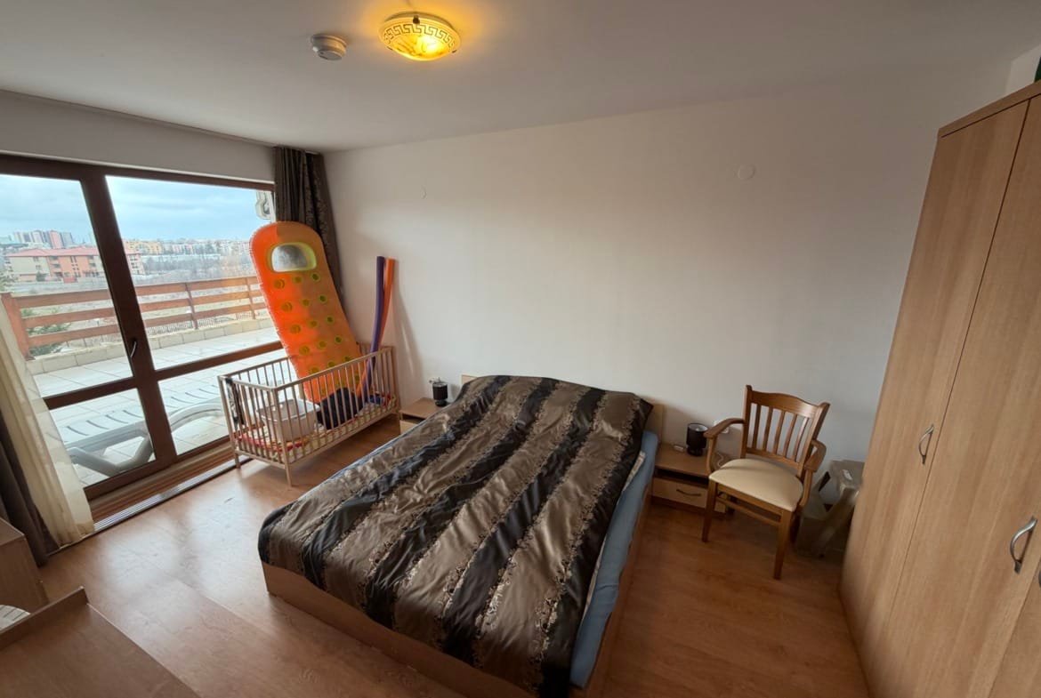 Современная спальня с двуспальной кроватью, комодом, креслом и детской кроваткой, выход на балкон с панорамным видом.