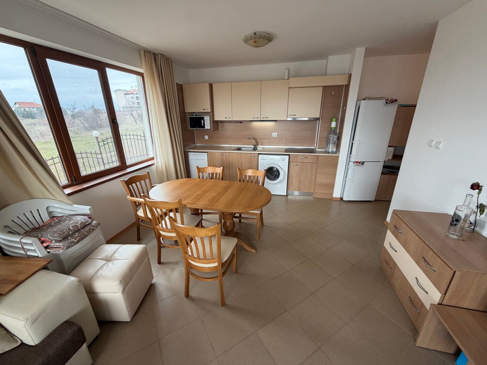 Современный трехкомнатный апартамент с кухней, обеденным столом, стиральной машиной и большими окнами с видом на природу.