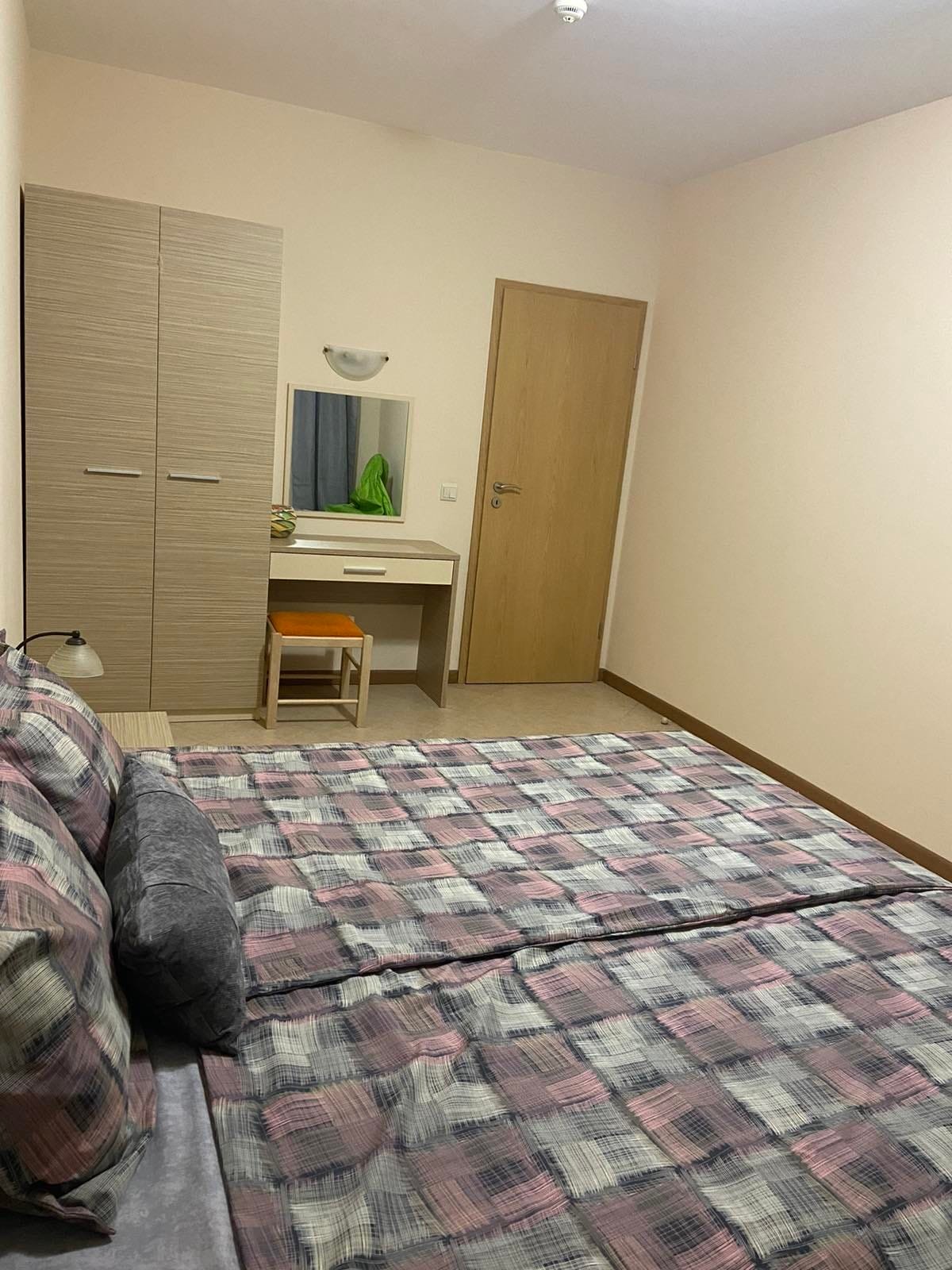 Современная двухкомнатная квартира с двуспальной кроватью, комодом и зеркалом в светлых тонах.