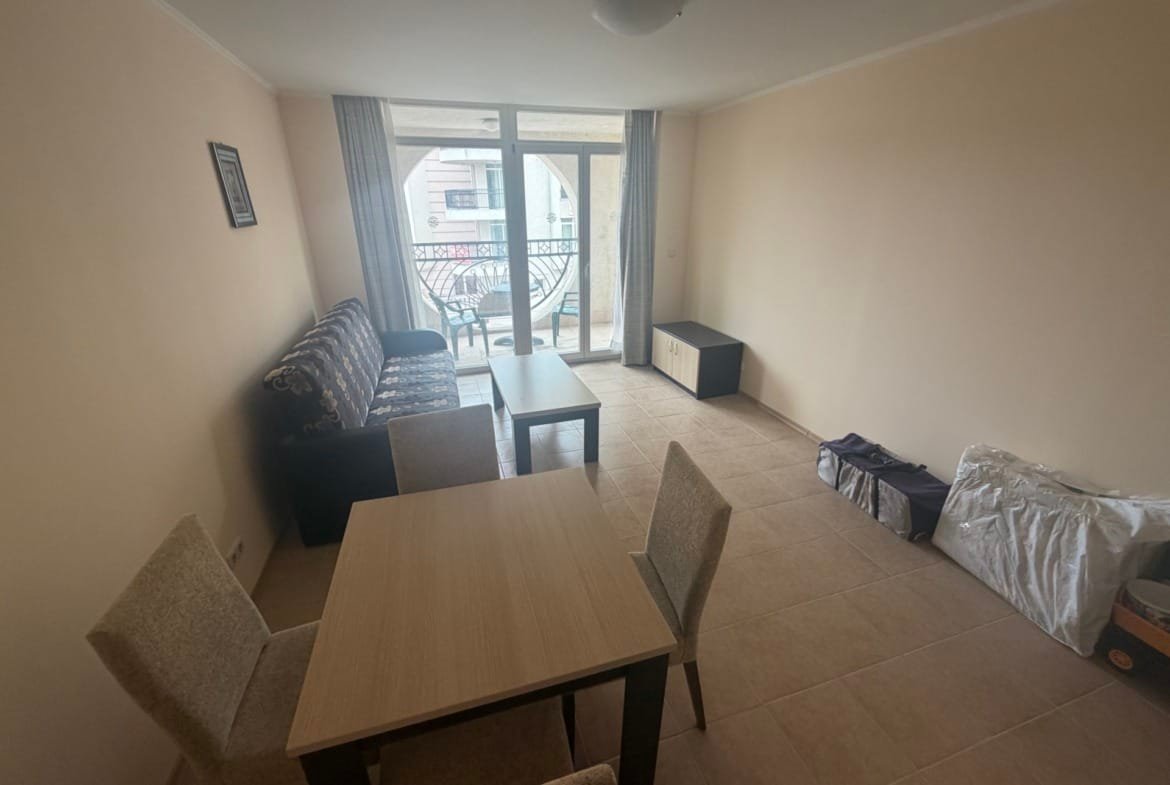 Современный двухкомнатный апартамент с диваном, столом и стульями, светлым оформлением и выходом на балкон.