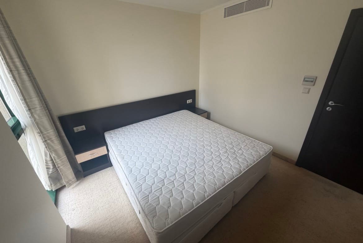 Двуспальная кровать без матраса в светлом комнате с окнами и нейтральными тонами, современный интерьер.