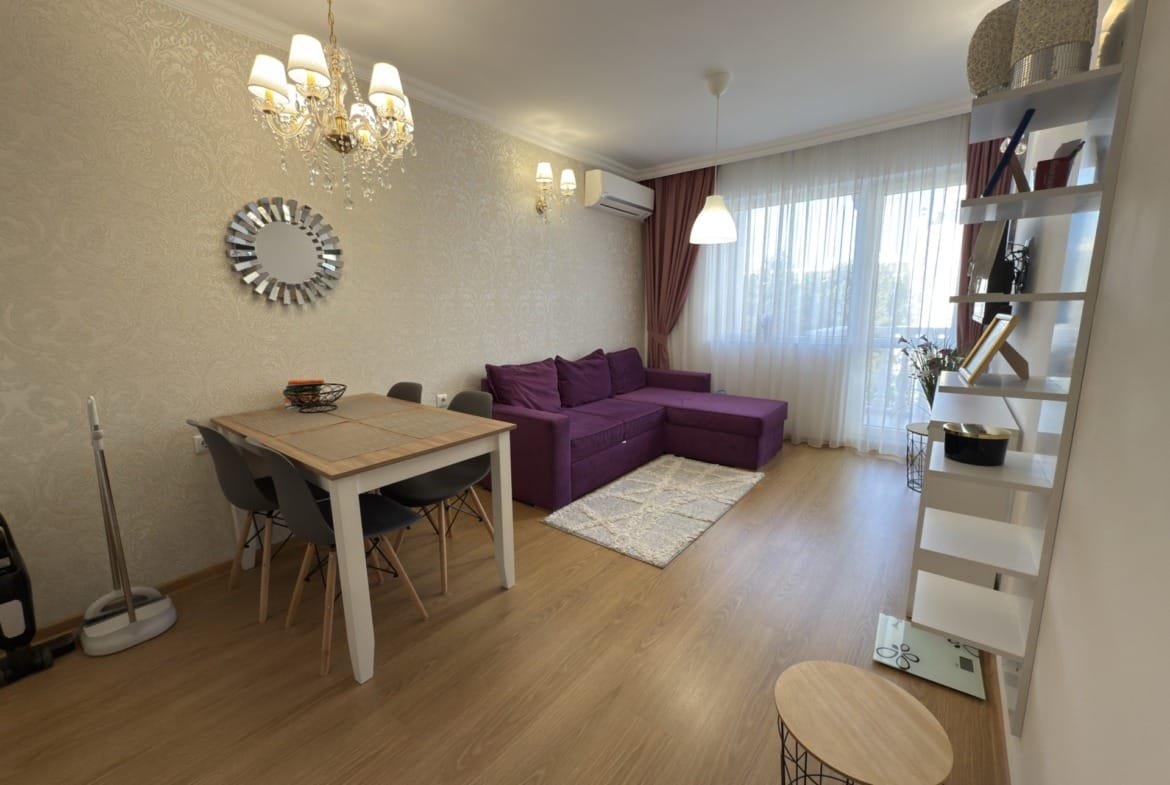 Современный интерьер трехкомнатного апартамента: стильная гостиная с фиолетовым диваном, обеденным столом и ярким освещением.