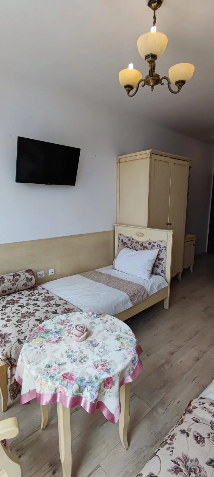Комната с одной кроватью и двумя местами для сидения, светлые тона, уютная обстановка, телевизор на стене.