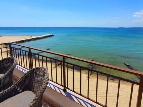 Балкон с плетёными креслами и видом на море, голубое небо и спокойная вода, идеальное место для отдыха у пляжа.